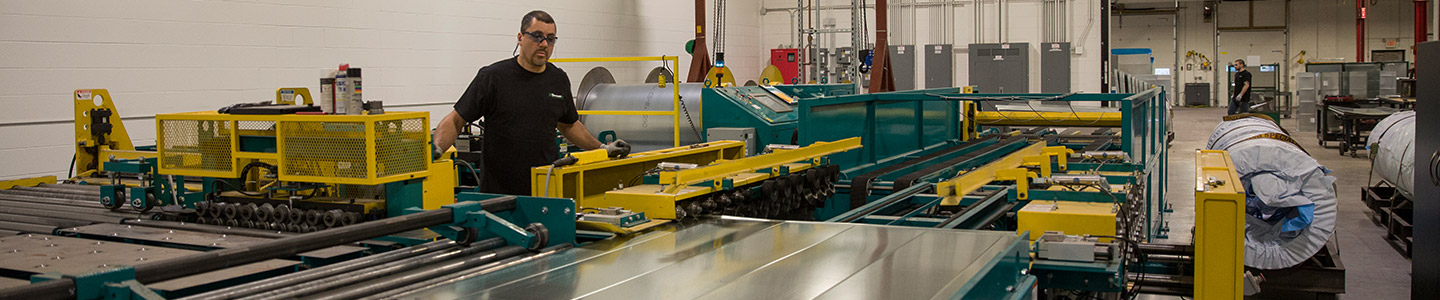Prefab line on the shop floor: gantry-mounted ductwork moving through a BuildCentrix customer's fabrication shop